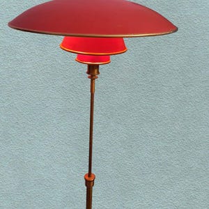 May include: A red and gold floor lamp with a large, round, red shade and three smaller, red shades. The lamp is on a tall, gold pole.