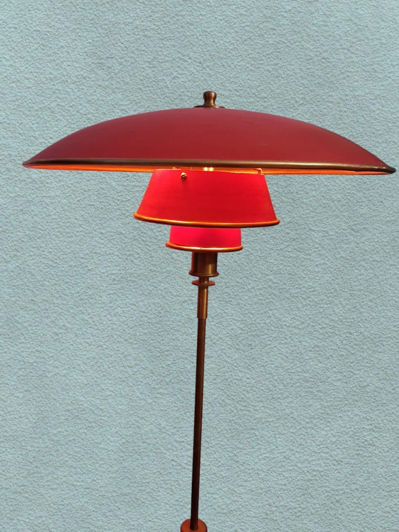 May include: A red and gold floor lamp with a large, round, red shade and a smaller, round, red shade. The lamp has a long, thin, gold stem.