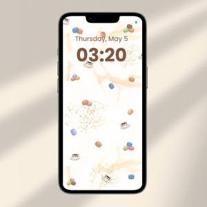Puede incluir: Pantalla de smartphone que muestra un fondo de pantalla caprichoso con un patrón de macarons coloridos y tazas de café esparcidas sobre un fondo beige claro. La hora es 03:20, con la fecha jueves 5 de mayo en la parte superior.