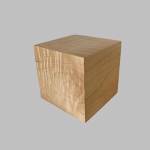 May include: A square wooden box made of light wood with a natural wood grain pattern.