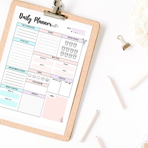May include: A printable daily planner with sections for top priorities, to do list, appointments, money tracker, meals, mood, gratitude, exercise, and water intake. The planner is on a corkboard with a clip.