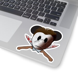 Puede incluir: Una pegatina con la cabeza de un ratón de dibujos animados con una máscara blanca y pelo marrón, con dos cuchillos ensangrentados cruzados detrás de la cabeza.