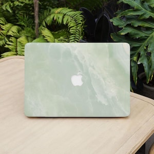 Könnte beinhalten: Eine grüne Marmor-Laptop-Haut mit einem weißen Apple-Logo.
