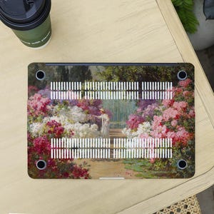 May include: Laptop case featuring a floral garden scene with a person in a white dress and hat. The case has a colorful design with pink, white, and red flowers. The case has a series of ventilation holes.