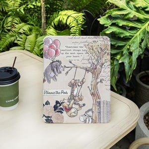 Può includere: Un quaderno con i personaggi di Winnie the Pooh, tra cui Pooh, Tigro ed Eeyore. La copertina ha un'estetica vintage con una citazione e dettagli floreali. Il titolo "Winnie the Pooh" è visibile.