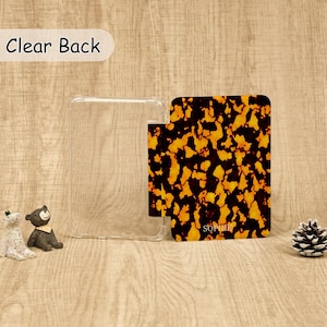 May include: A rectangular protective case featuring a clear back panel and a hinged cover with a brown and black tortoiseshell pattern. The name SOPHIE is printed in small white letters on the lower portion of the patterned cover section.