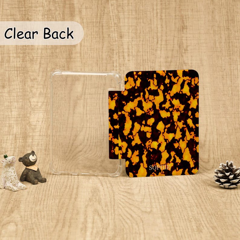 May include: A rectangular protective case featuring a clear back panel and a hinged cover with a brown and black tortoiseshell pattern. The name SOPHIE is printed in small white letters on the lower portion of the patterned cover section.