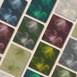 Può includere: Una collezione di quaderni rettangolari caratterizzati da un motivo floreale a fuoco morbido. Le copertine presentano vari colori tra cui blu profondo, verde bosco, salvia, bordeaux e giallo, ognuno con un design floreale etereo e traslucido.