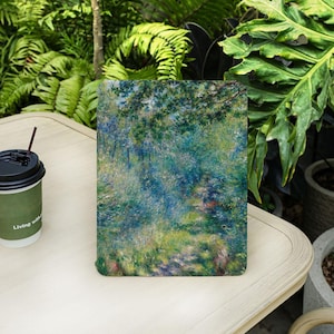 Puede incluir: Una impresión artística cuadrada que presenta una pintura impresionista colorida de un paisaje natural con azules, verdes y amarillos. A la izquierda hay una taza de café desechable con tapa negra y pajita. La taza tiene la inscripción "Living with".