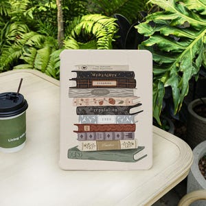 Könnte beinhalten: Eine beige Handyhülle mit einem darauf gedruckten Stapel Bücher. Die Bücher haben Titel wie "Midnights", "Evermore", "Reputation" und "1989".