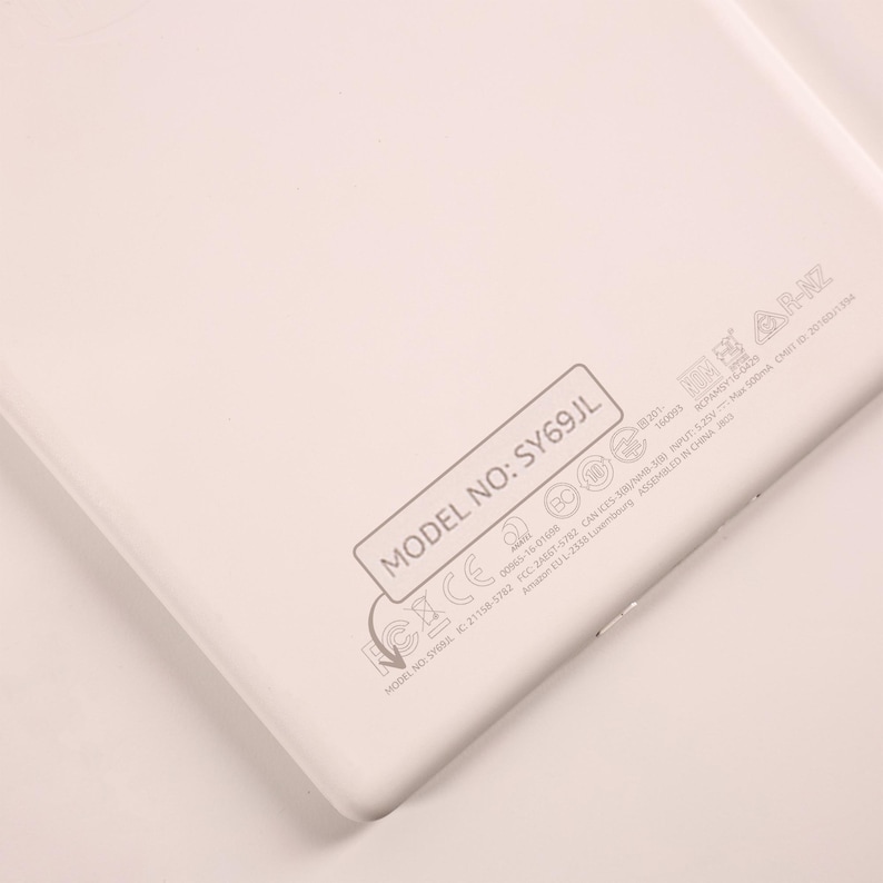 May include: A white electronic device back panel featuring the text MODEL NO: SY69JL enclosed in a rectangular border. Below this, various regulatory symbols, certification marks, and technical specifications are printed in light gray ink.