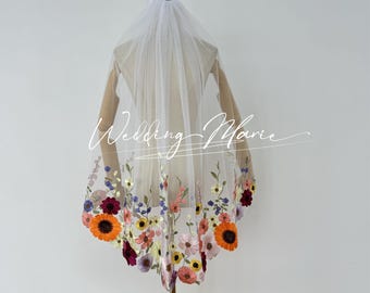 May include: White bridal veil with a floral embroidered border. The embroidery features a variety of colorful flowers, including orange, yellow, pink, purple, and red.