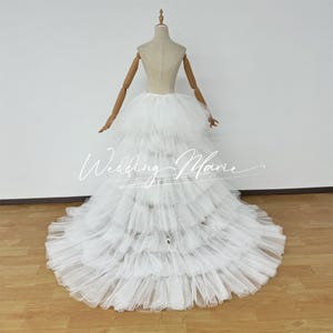 Puede incluir: Enagua de tul blanco para boda con múltiples capas, creando una falda llena y voluminosa. La enagua se muestra en un maniquí.