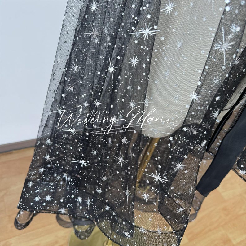 May include: Black tulle fabric with silver glitter stars. The fabric is sheer and has a delicate texture.