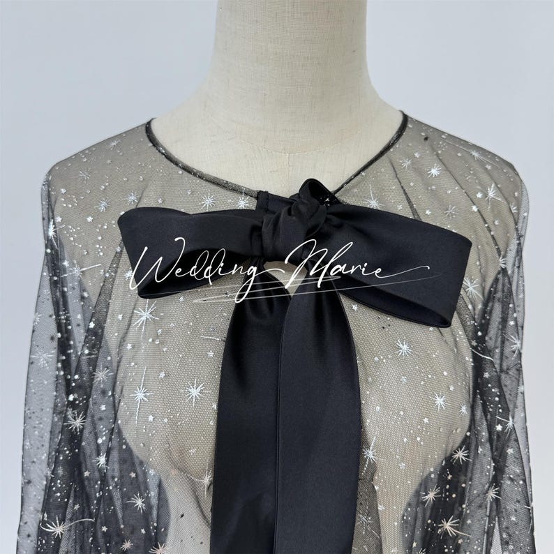 May include: Black sheer overlay with silver glitter stars and a black satin bow. The overlay has a loose fit and is perfect for adding a touch of sparkle to any outfit.