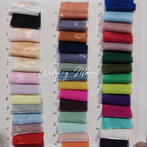 Puede incluir: Una carta de colores con muestras de tela en una variedad de colores, incluyendo rosa, azul, verde y morado. Las muestras est&aacute;n dispuestas en columnas verticales, con cada muestra midiendo aproximadamente 2,5 cm por 2,5 cm. El fondo es una cuadr&iacute;cula.