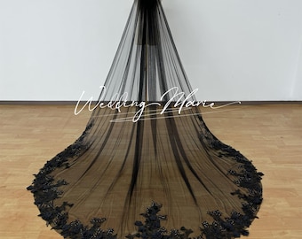 May include: A long, black bridal veil with a floral lace trim along the bottom edge. The veil is made of a sheer fabric and is displayed on a mannequin. The text "Wedding Marie" is written across the veil.