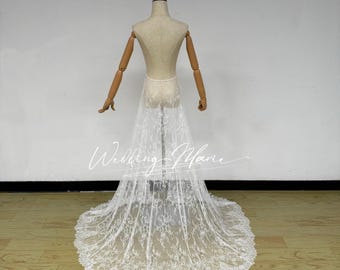 Puede incluir: Una falda de novia de encaje blanco con una larga cola se exhibe en un maniquí. La falda es transparente, revelando la forma del maniquí. El patrón de encaje es intrincado.
