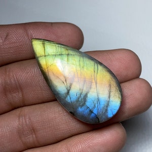 Peut inclure: Une pierre précieuse de labradorite en forme de larme avec des couleurs irisées bleues, vertes et jaunes.