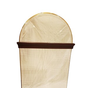 May include: A tall, arched mirror with a dark wood frame and a gold trim. The mirror has a beveled edge and a slightly cloudy reflection.