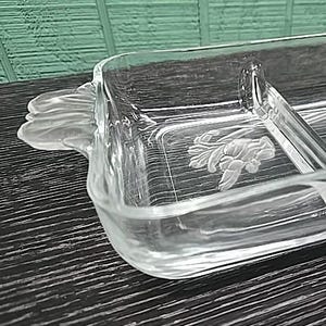 May include: Clear glass serving dish with three compartments and floral detailing. The rectangular dish has a handle on one side and is designed for serving appetizers or snacks. The glass is transparent, allowing the contents to be visible.