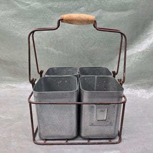 May include: A metal caddy with four square containers and a wooden handle. The caddy is rusty brown and the containers are silver.