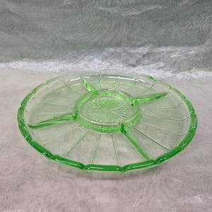 May include: A vintage green glass divided serving dish with a scalloped edge. The dish has six sections and a central dip.