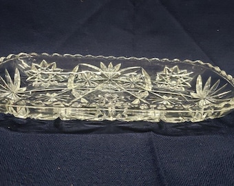 May include: A clear glass oval dish with a scalloped edge and a cut glass design. The dish has a starburst pattern.