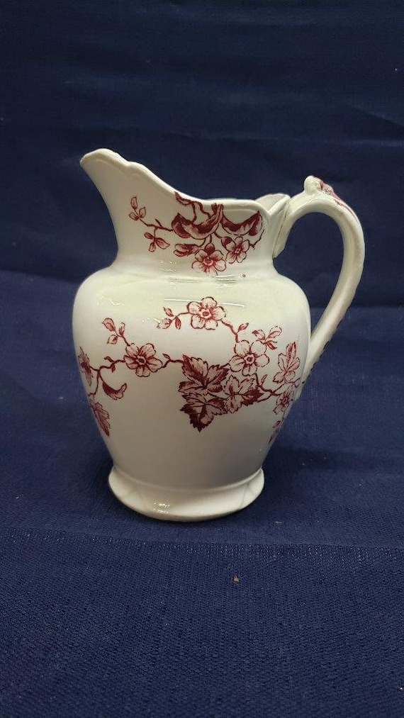 White pitcher with red flowers