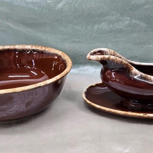 May include: A brown and white glazed ceramic bowl and a matching gravy boat with a handle. The bowl and gravy boat are both in a brown and white glaze pattern.