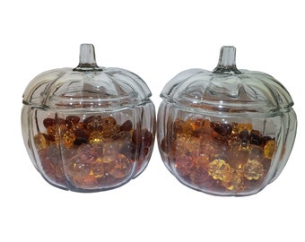 May include: Two clear glass pumpkin-shaped jars with lids filled with amber and yellow glass beads.