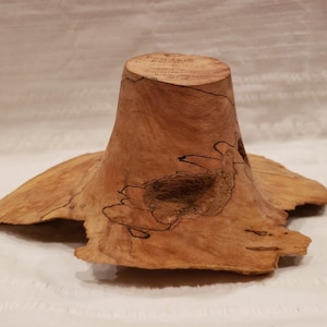 May include: A wooden bowl with a natural, brown, and beige finish. The bowl has a unique, irregular shape and a smooth, polished surface.