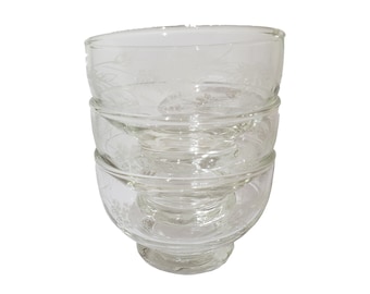 May include: A set of three clear glass bowls with a delicate etched floral design. The bowls are stacked on top of each other.