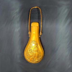 May include: A gold-coloured metal powder horn with a leather strap. The horn is decorated with an embossed image of a person hunting a deer.