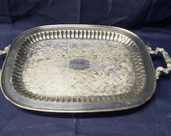 Può includere: Un vassoio da portata in argento con manici decorativi e un design in rilievo decorativo. Il vassoio è rettangolare con angoli arrotondati.