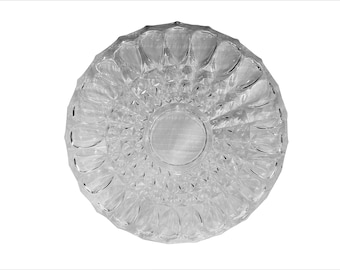 May include: Clear, round glass ashtray with a detailed, textured pattern. The ashtray features a central circular indentation and a series of petal-like shapes around the rim. The design is symmetrical and reflects light, creating a sparkling effect.