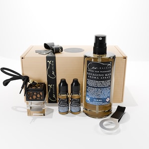 Könnte beinhalten: Ein Geschenkset für Autoduft mit einer beigen Box, schwarzem Band und verschiedenen Aromaprodukten. Das Set enthält eine 250-ml-Flasche "Savaging Man" Aroma-Spray, zwei kleine Flaschen und einen Lüftungsclip.