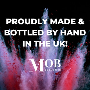 Puede incluir: Una explosi&oacute;n colorida de polvo rojo y morado sobre un fondo negro. El texto "Proudly Made & Bottled by Hand in the UK!" se muestra sobre el texto "MOB Cosmetics".