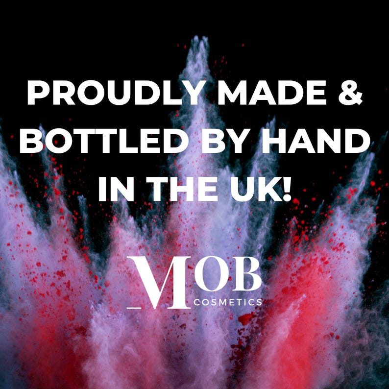 Puede incluir: Una explosi&oacute;n colorida de polvo rojo y morado sobre un fondo negro. El texto "Proudly Made & Bottled by Hand in the UK!" se muestra sobre el texto "MOB Cosmetics".