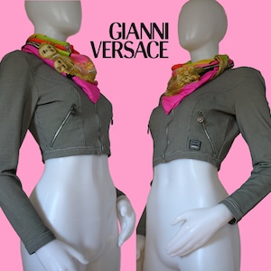 May include: A black and white cropped jacket with a zipper closure and a Gianni Versace label. The jacket has two pockets on the front and a contrasting white stitching detail.