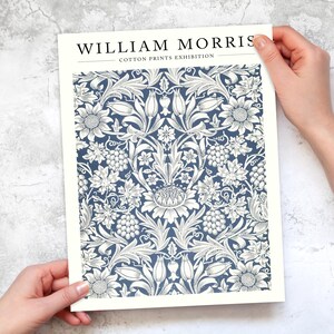 Puede incluir: Un p&oacute;ster blanco con el texto "WILLIAM MORRIS COTTON PRINTS EXHIBITION" en la parte superior. El p&oacute;ster presenta un patr&oacute;n floral azul y blanco.