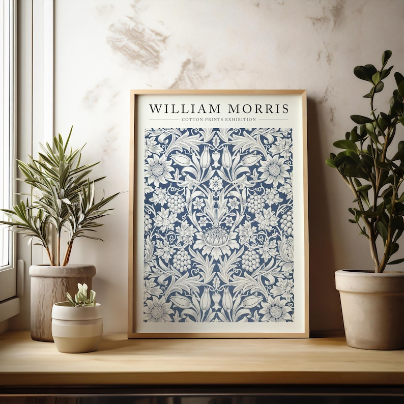 Puede incluir: Una impresi&oacute;n enmarcada de un patr&oacute;n floral azul y blanco con el texto "WILLIAM MORRIS - COTTON PRINTS EXHIBITION" en la parte superior.