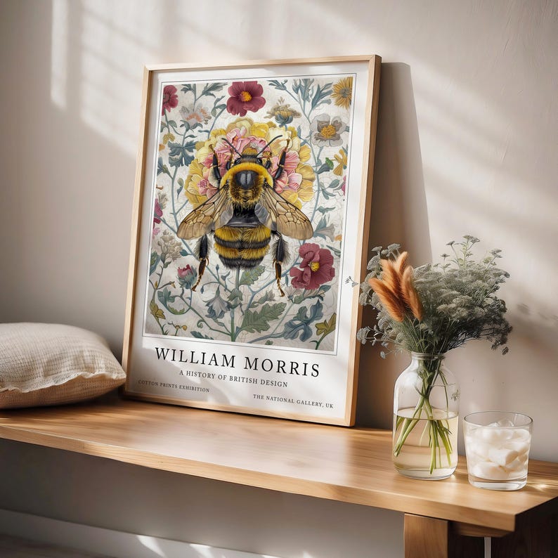 May include: A framed print of a bee surrounded by flowers. The print is titled "William Morris: A History of British Design" and is from the Cotton Prints Exhibition at The National Gallery, UK.