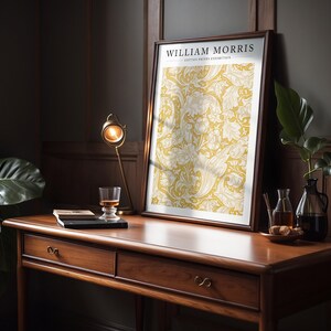 May include: A framed print of a yellow and white floral pattern with the text "WILLIAM MORRIS COTTON PRINTS EXHIBITION" at the top.