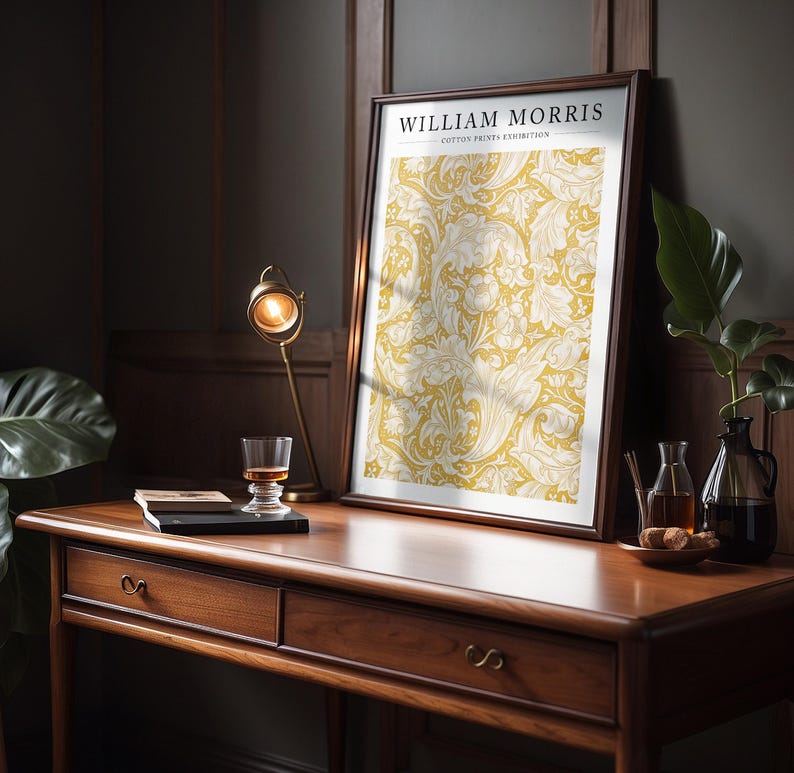 May include: A framed print of a yellow and white floral pattern with the text "WILLIAM MORRIS COTTON PRINTS EXHIBITION" at the top.