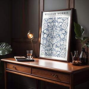 Puede incluir: Una impresi&oacute;n enmarcada de un patr&oacute;n floral azul y blanco con el texto "WILLIAM MORRIS COTTON PRINTS EXHIBITION" en la parte superior.