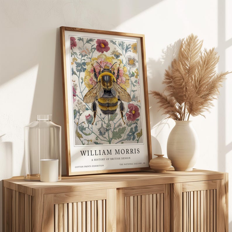 May include: A vintage poster featuring a bee surrounded by flowers. The poster is titled "William Morris: A History of British Design" and is from the Cotton Prints Exhibition at the National Gallery.
