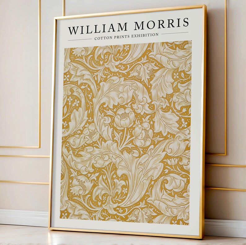 May include: A gold framed poster with the text "WILLIAM MORRIS - COTTON PRINTS EXHIBITION" at the top. The poster features a repeating pattern of white stylized leaves and flowers on a yellow background.