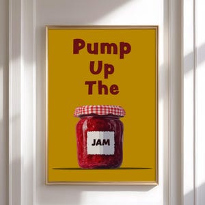 Pode incluir: Impressão emoldurada com fundo amarelo e as palavras "Pump Up The" em bordô. Abaixo, um pote de geleia com tampa xadrez vermelha e branca e um rótulo branco com a palavra "JAM".