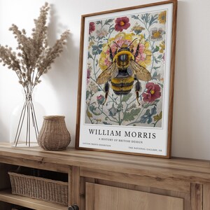May include: A vintage poster featuring a bee surrounded by colorful flowers. The poster is titled "William Morris: A History of British Design" and includes the text "Cotton Prints Exhibition" and "The National Gallery, UK".